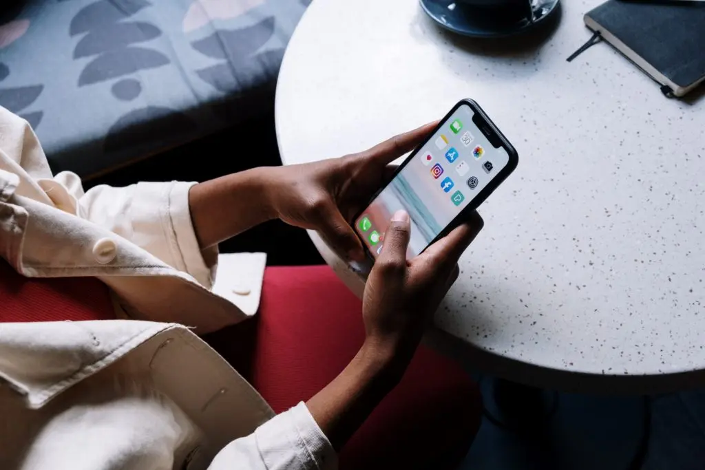 Zoom sur l'écran d'un téléphone portable tenu dans les mains d'une personne assise dans un café
