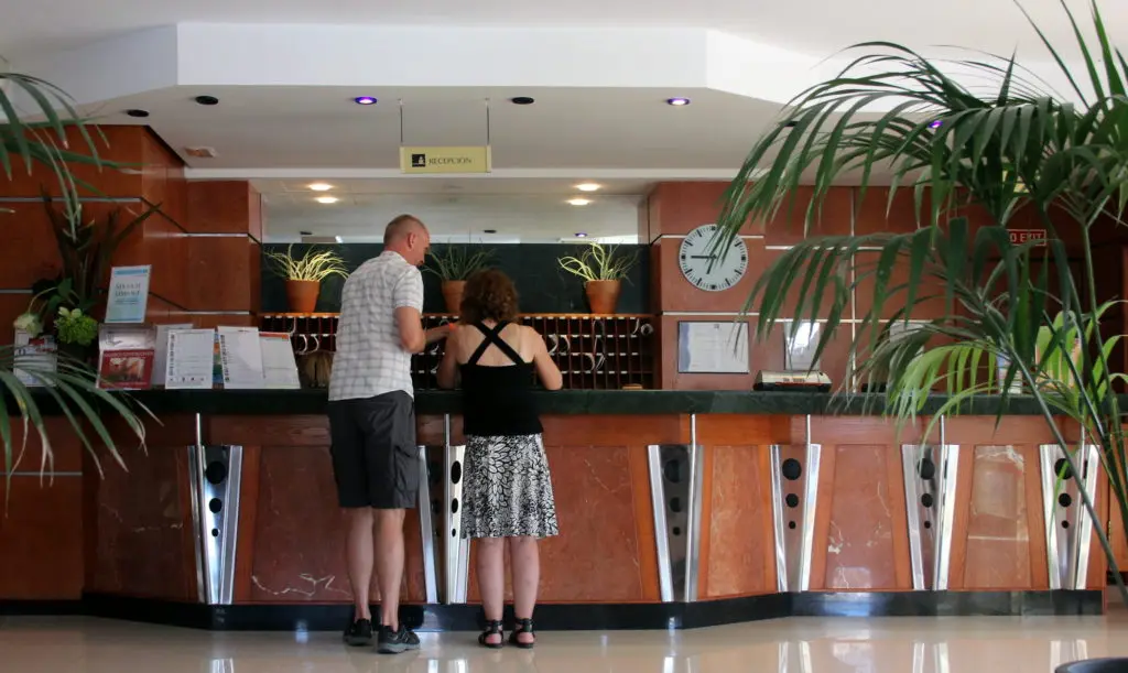 Une réception d'hôtel : deux clients debout devant le comptoir